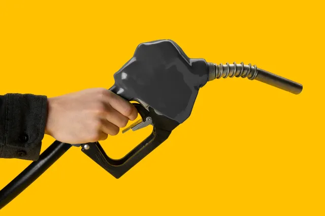 A hand holding a gas pomp infront of a yellow background