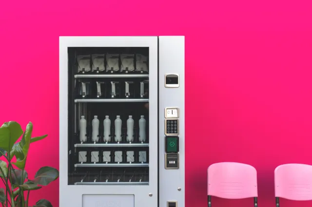 A vending machine in front of a pink wall